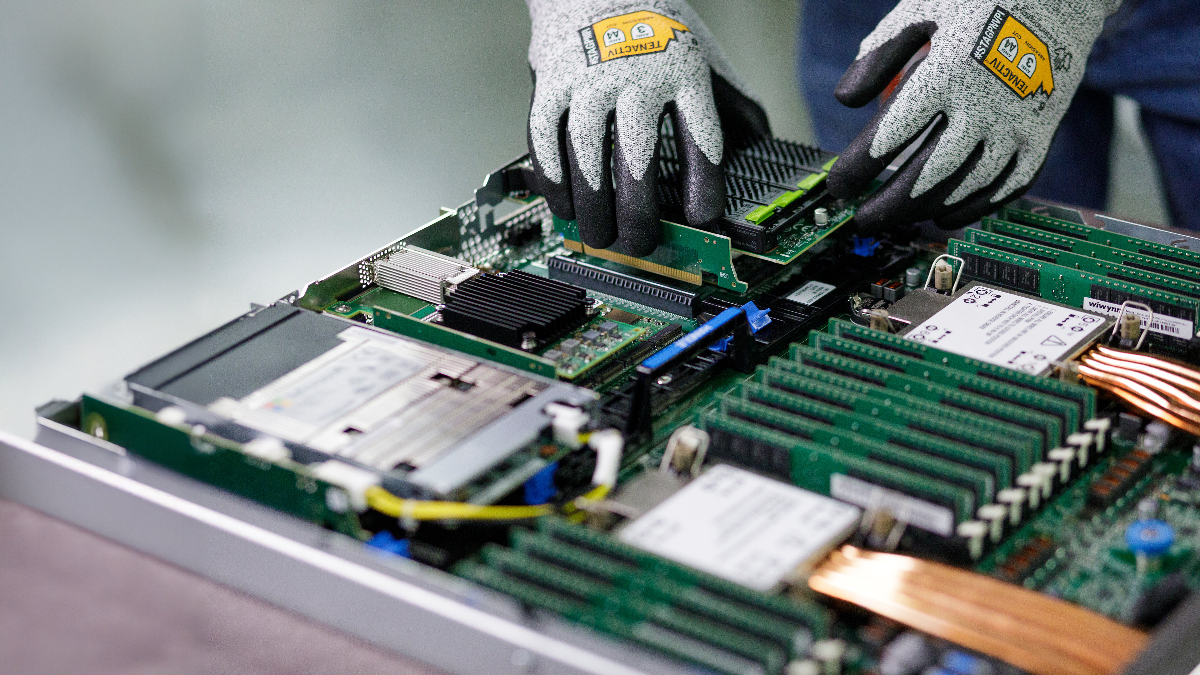 A person wearing gloves is installing a computer component on a server motherboard.