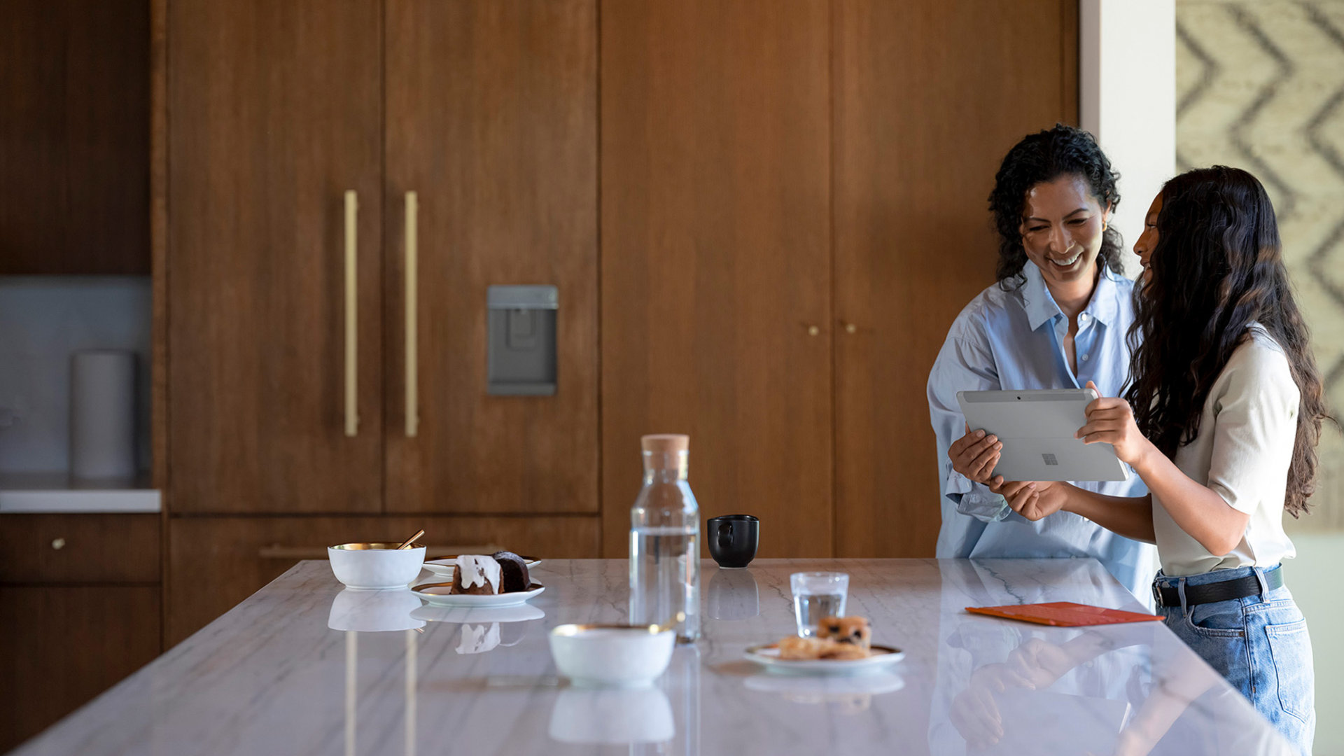 A parent and child use Surface Go 3 in their kitchen.