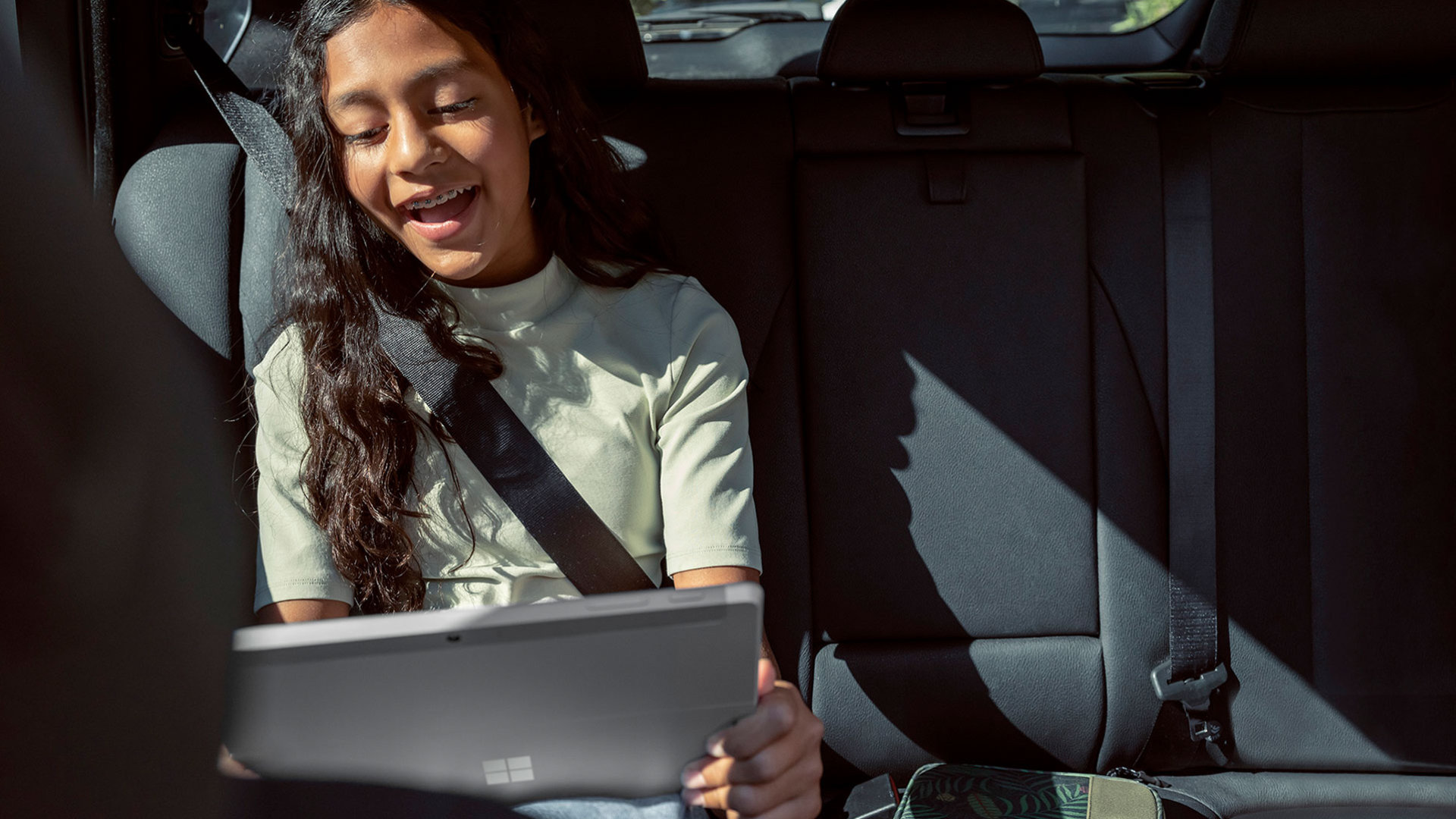Uma criança a utilizar o Surface Go 3 no carro.