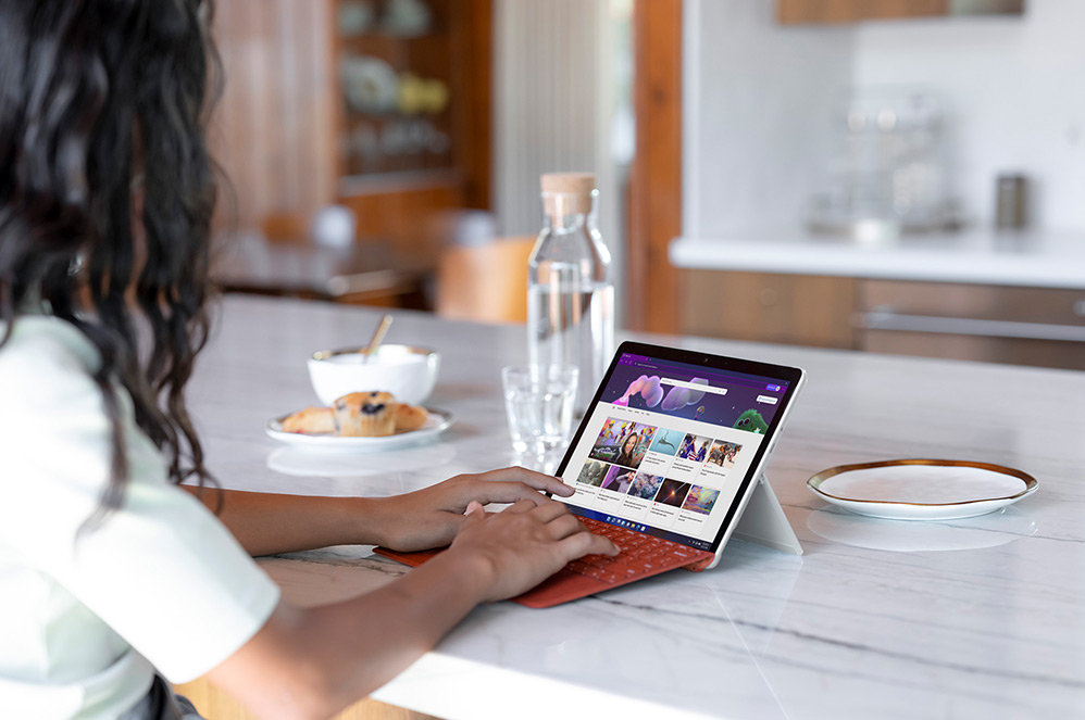 Kind verwendet Surface Go 3 als Laptop an Küchentresen.