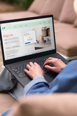 Person typing on a laptop displaying a sign-in page and a pop-up notification in a casual setting.