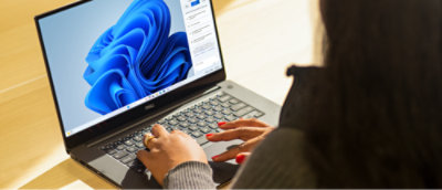A person uses a Dell laptop, in a bright indoor setting.