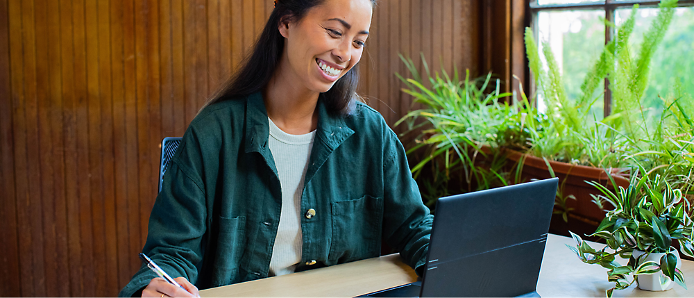 笑顔でノート PC で作業している女性