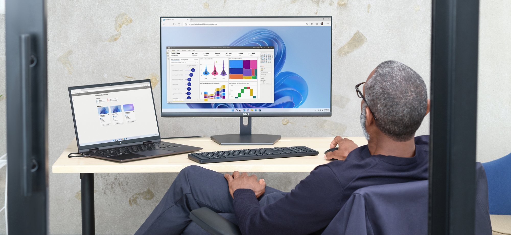 Een man controleert gegevensgrafieken op een computerscherm en laptop in een kantooromgeving.