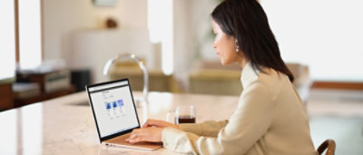 Een vrouw die aan een tafel zit en een laptop gebruikt.