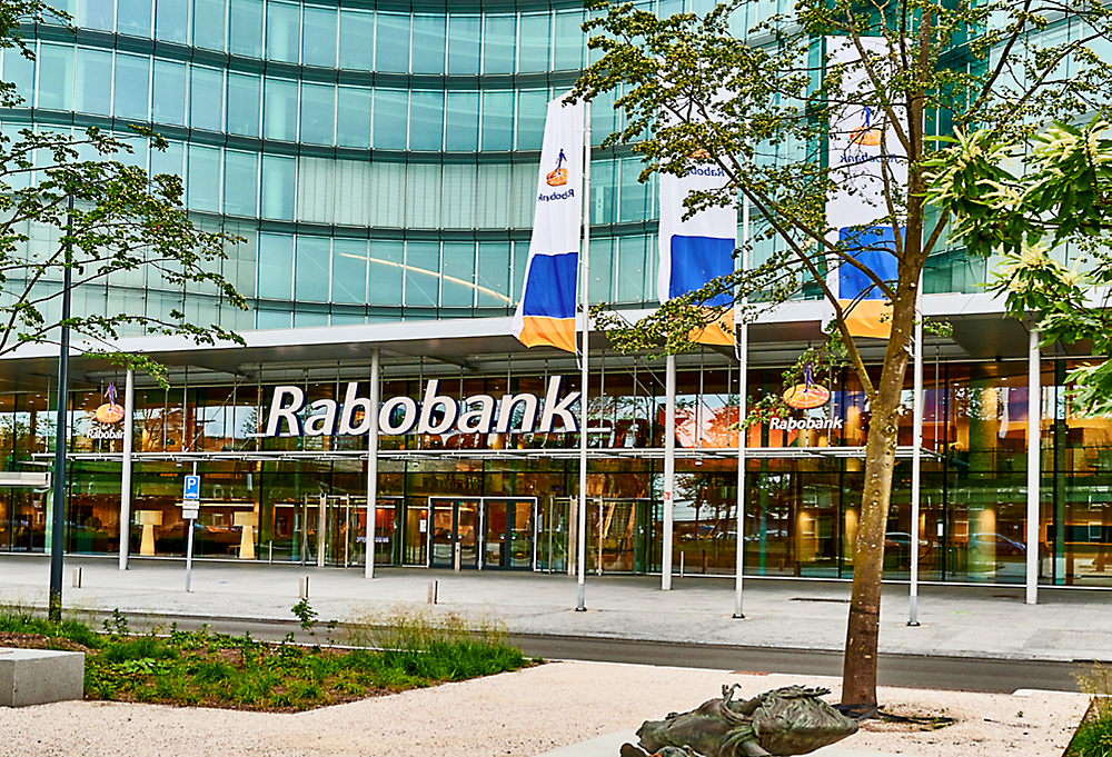 Um edifício Rabobank com bandeiras à frente.