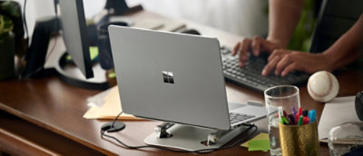 A laptop on a desk with a person typing on the keyboard