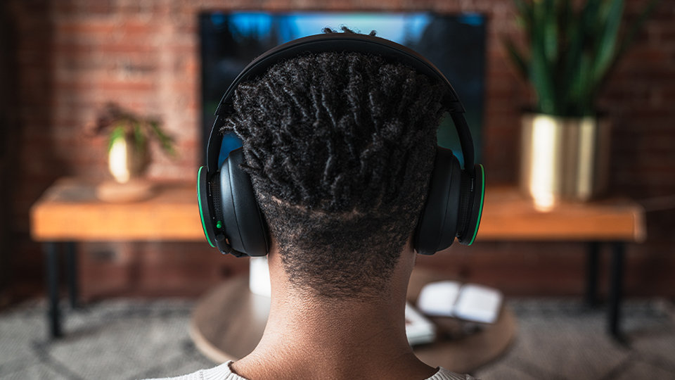 A person wearing the Xbox Wireless Headset while gaming on a couch.