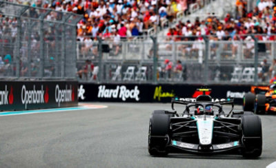 Formula racing car driving on track with crowd-filled grandstand