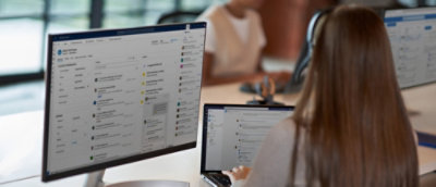 两位专业人员在使用电脑工作，大屏幕上显示项目管理软件界面