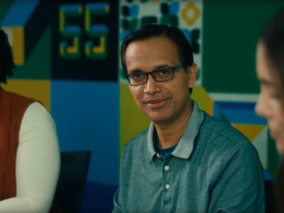 Three people are sitting together in a meeting room with colorful walls.