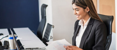 A person sitting at a table holding papers.