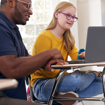 Moški in ženska sedita za mizo in gledata v prenosnik.