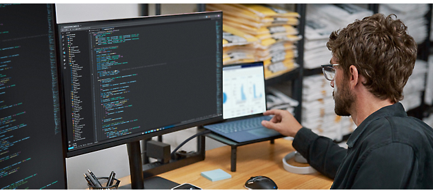 Dezvoltatorul de software lucrează la cod la o stație de lucru cu monitor dual.