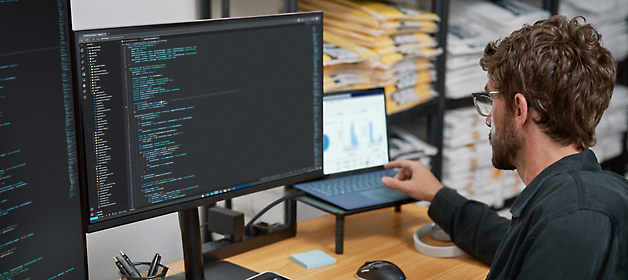 Software developer working on code at a dual-monitor workstation.