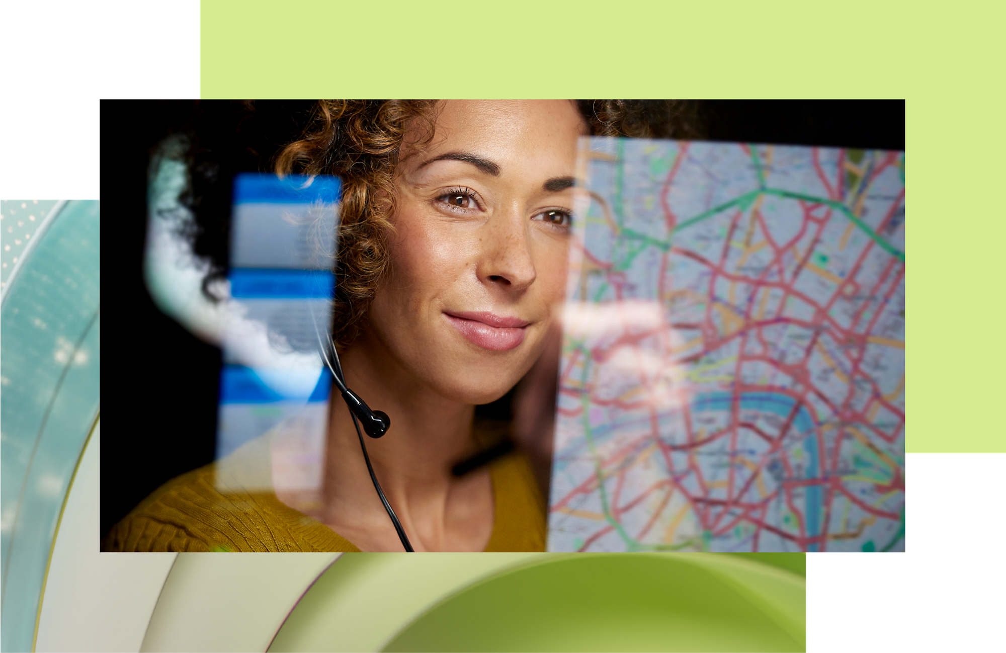 Asiakaspalveluedustaja, jolla on kuulokemikrofoni, hymyilee katsoessaan karttaa digitaalisella näytöllä