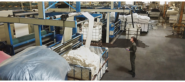 Un trabajador realiza maniobras con una carreta en una instalación de lavandería industrial.