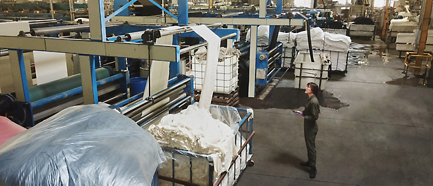 A worker maneuvering a cart through an industrial laundry facility.