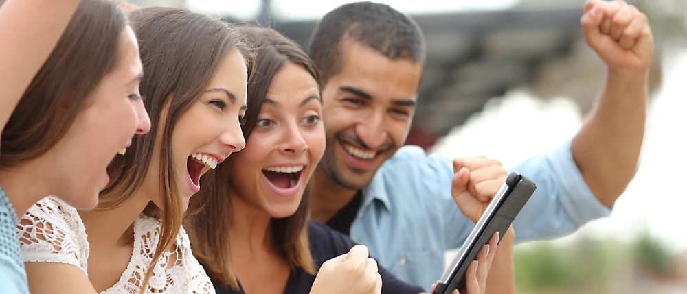 Eine Gruppe von lachenden Personen, die auf ein Tablet schauen