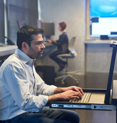 A man and women sitting at a table with a laptop in front of them.
