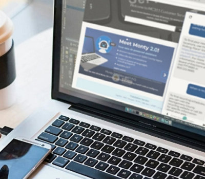 A laptop with a cell phone and a cup of coffee on a table.