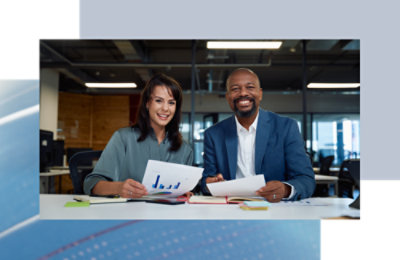 A man and woman sitting at a table holding papers.