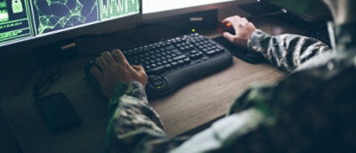 A military man working on desktop screen in office.