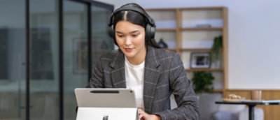 A person wearing headphones and looking at a tablet.