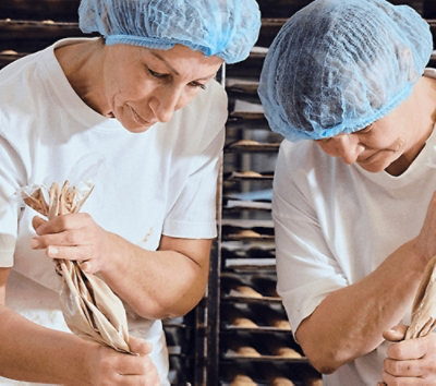 A close-up of people wearing blue hair nets and white shirts.
