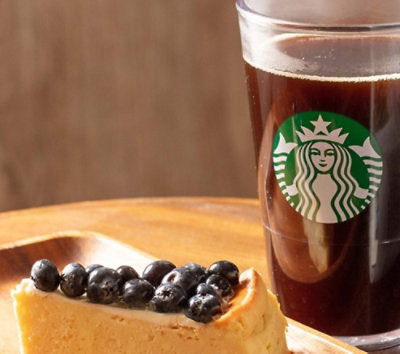 A slice of cheesecake with blueberries on a wooden plate.