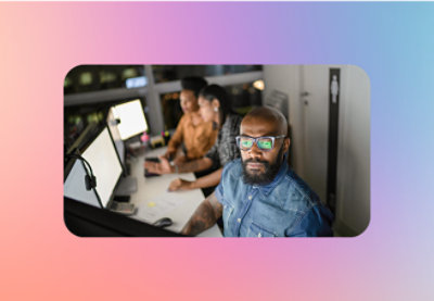 A man sitting at a desk with a group of people in the background.