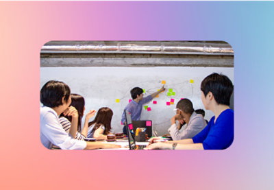 A group of people in a classroom writing on a whiteboard.
