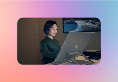 A woman with short dark hair sitting at a desk looking at a computer.