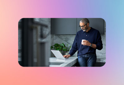 A man holding a cup and using a laptop.