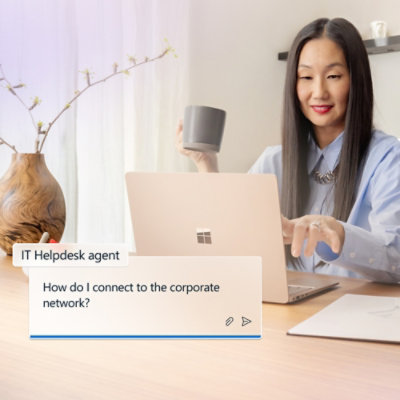 Egy csészét tartó és közben egy laptopot néző nő.