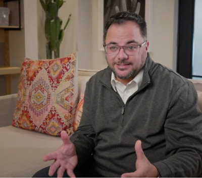 A man with glasses and a mustache sitting on a couch.