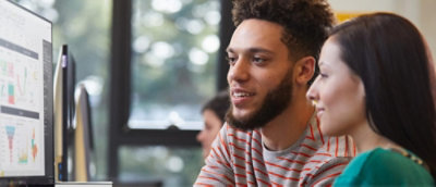 En mand og en kvinde ser på en stationær computer på kontoret.