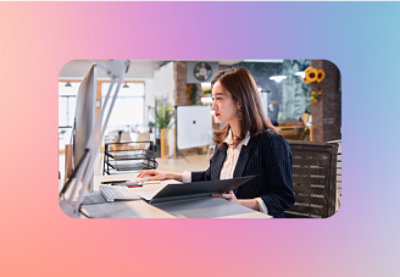 A woman sitting at a desk looking at a Desktop screen.