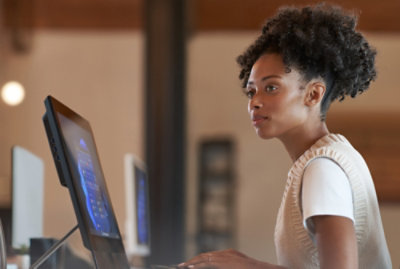 Eine Frau mit lockigen Haaren, die auf einen Computerbildschirm blickt.
