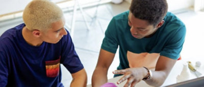 Zwei Personen, die an einem Tisch sitzen und sich anschauen.