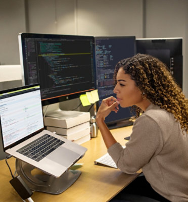 A woman sitting at a desk with two computers
