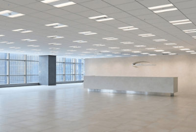Large empty office with white ceiling, lights, pillar, and tile floor.