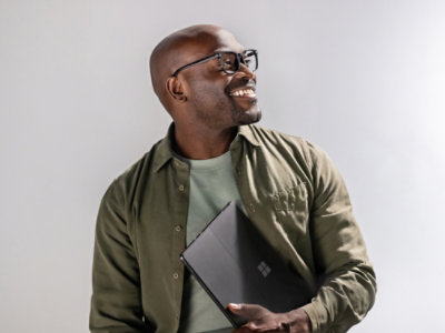 A man holding a laptop while smiling with glasses