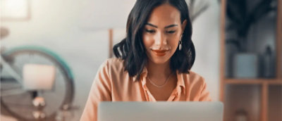 A women smiling and working on a laptop