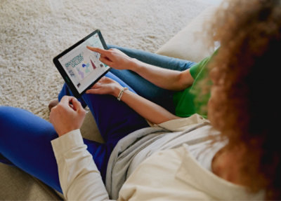 Một người đàn ông và phụ nữ đang ngồi trên đi văng và dùng máy tính bảng.