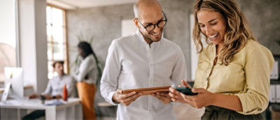 A woman smiling while holding a phone and a man holding a tray.