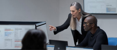 A woman pointing at a computer screen and a man looking at screen.
