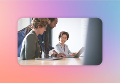 Three professionals engaged in a collaborative discussion around a laptop in a modern office setting.