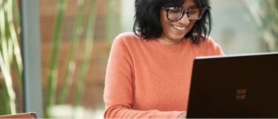 A woman smiling while using a laptop.