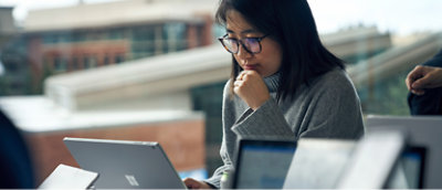A woman looking at a laptop with her hand on her chin.